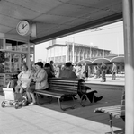 164180 Afbeelding van wachtende rezigers op het stadsbusstation op het Stationsplein te Arnhem, met op de achtergrond ...